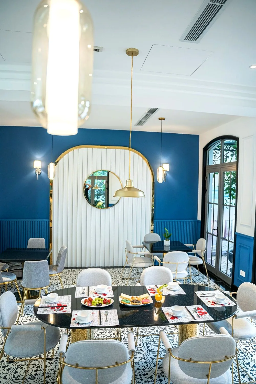 Blue Indochine dining salon with gold arch and encaustic tile floor