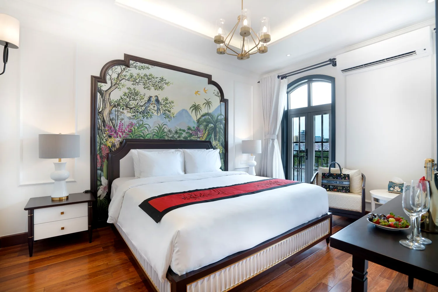 La Rose Luxury room with an ornately framed tropical jungle mural, red bed runner and chandelier