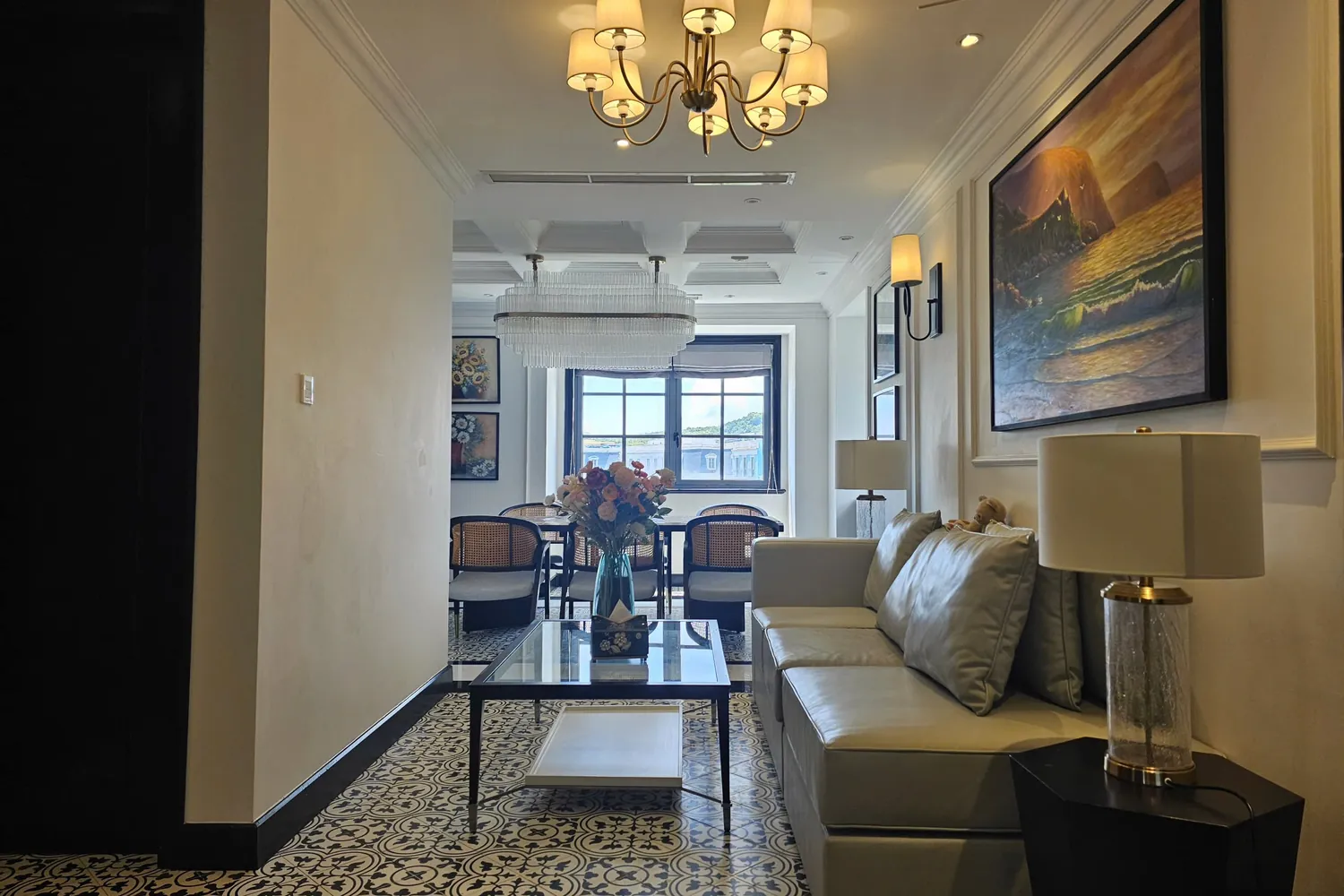 La Rose Penthouse living room with a leather sofa and chandelier, the dining table for six behind