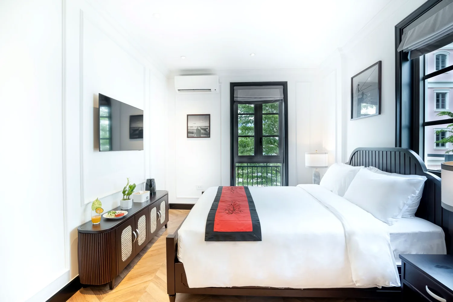 Bright La Rose Premier Corner room with white linens, a red-and-black runner and French windows